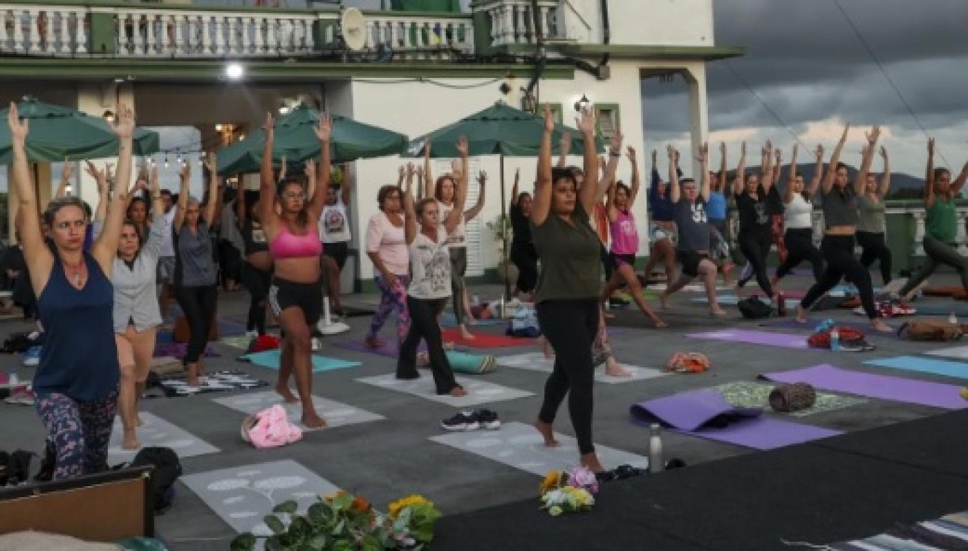 pessoas estão em pé com os braços para cima em movimento de ioga. #paratodosverem 