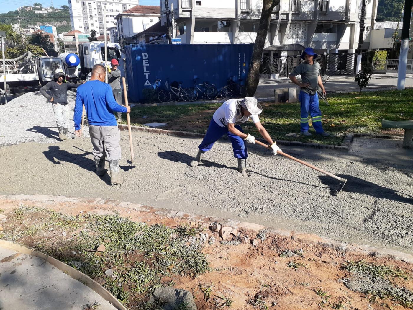 homens estão concretando passeio de praça. #paratodosverem