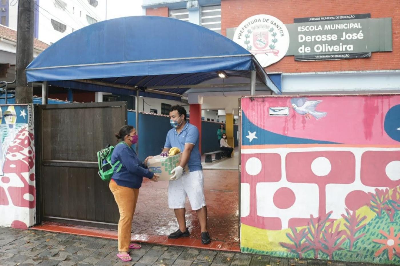 Mulher pega cesta básica em porta de escola. Homem faz a entrega. #Paratodosverem