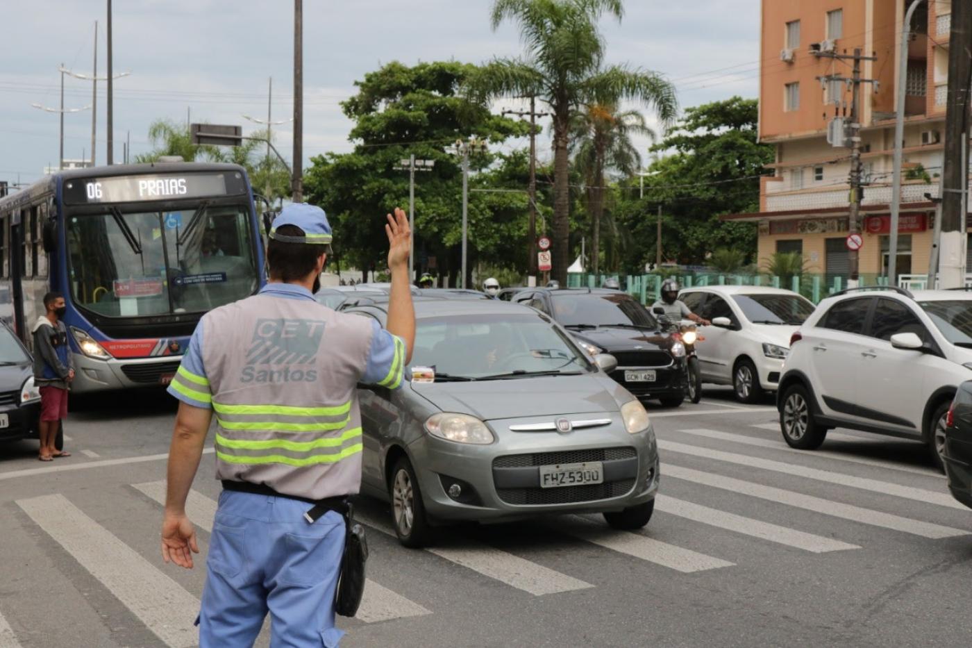 Agente está na pista, próximo a uma faixa de segurança. Ele sinalizada para carros em movimento. #Paratodosverem
