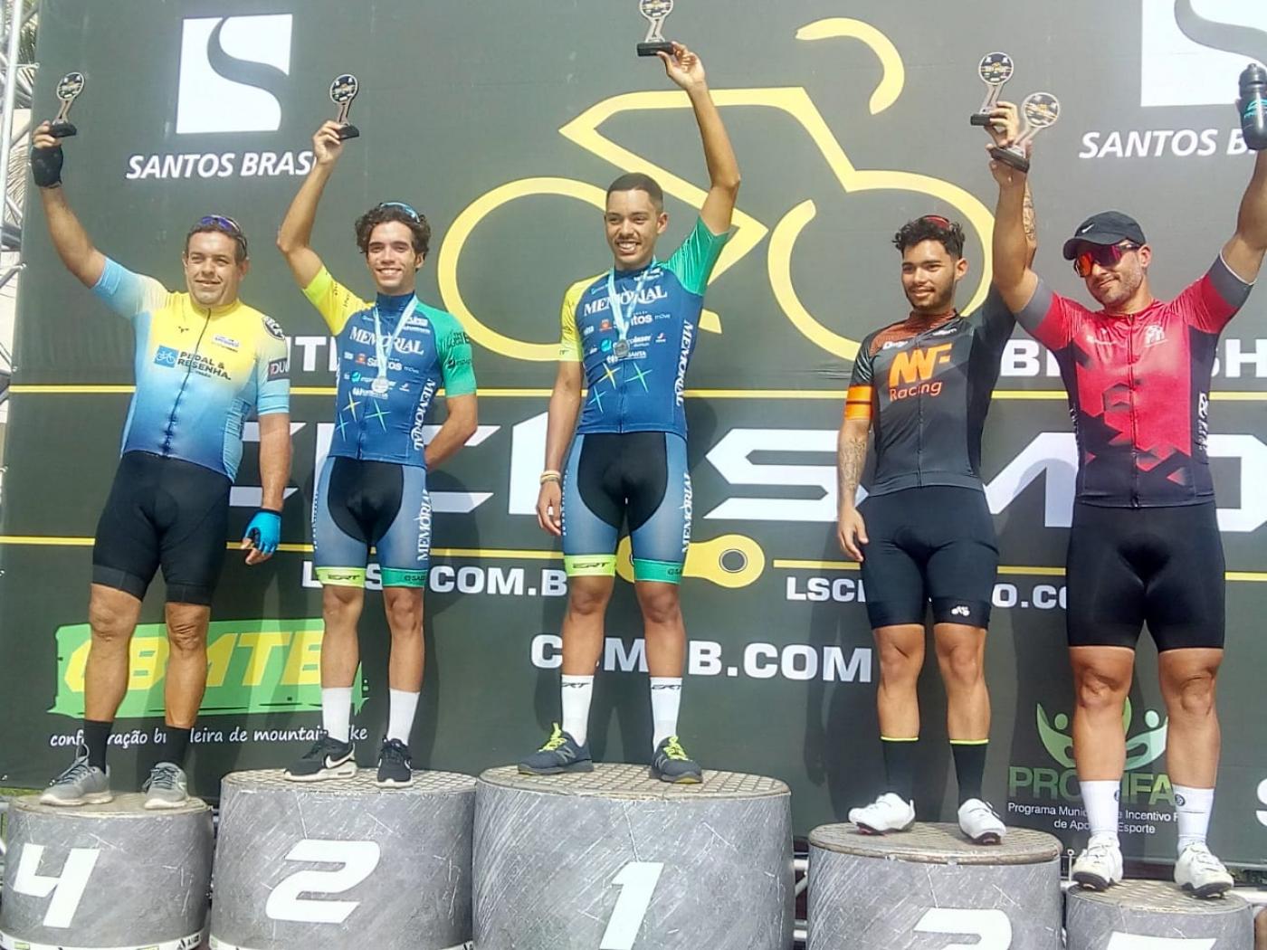 pódio  masculino, com cinco homens. O primeiro e o segundo lugar usam o uniforme azul da Fupes. #paratodosverem