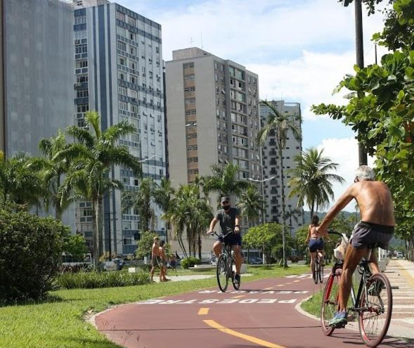 Ciclistas pedalam em ciclovia na Ponta da Praia. #pracegover