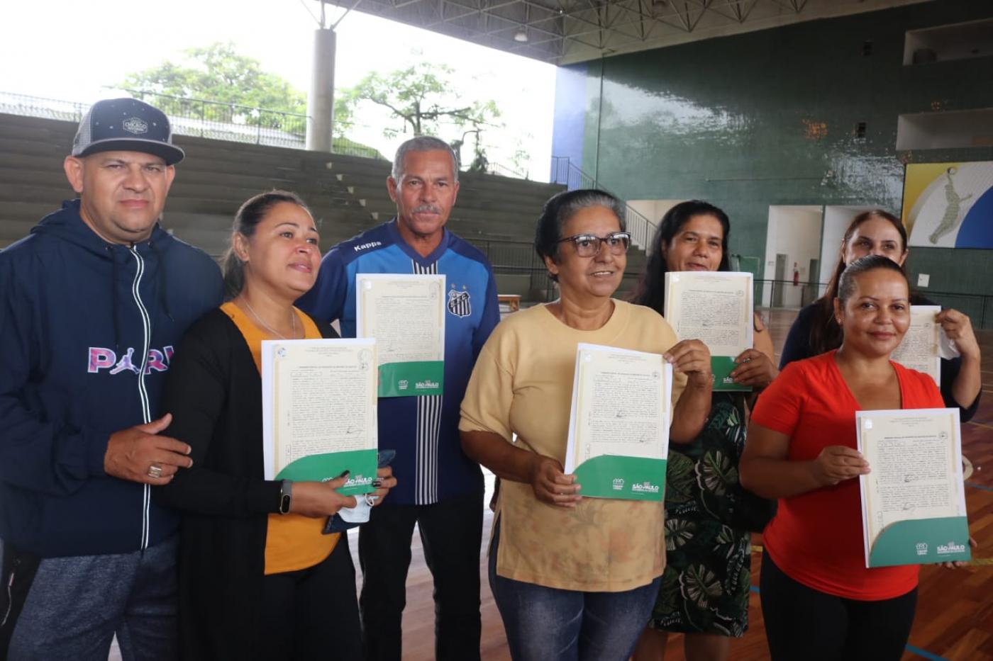 Alguns proprietários posam para foto segurando seus respectivos títulos. #paratodosverem