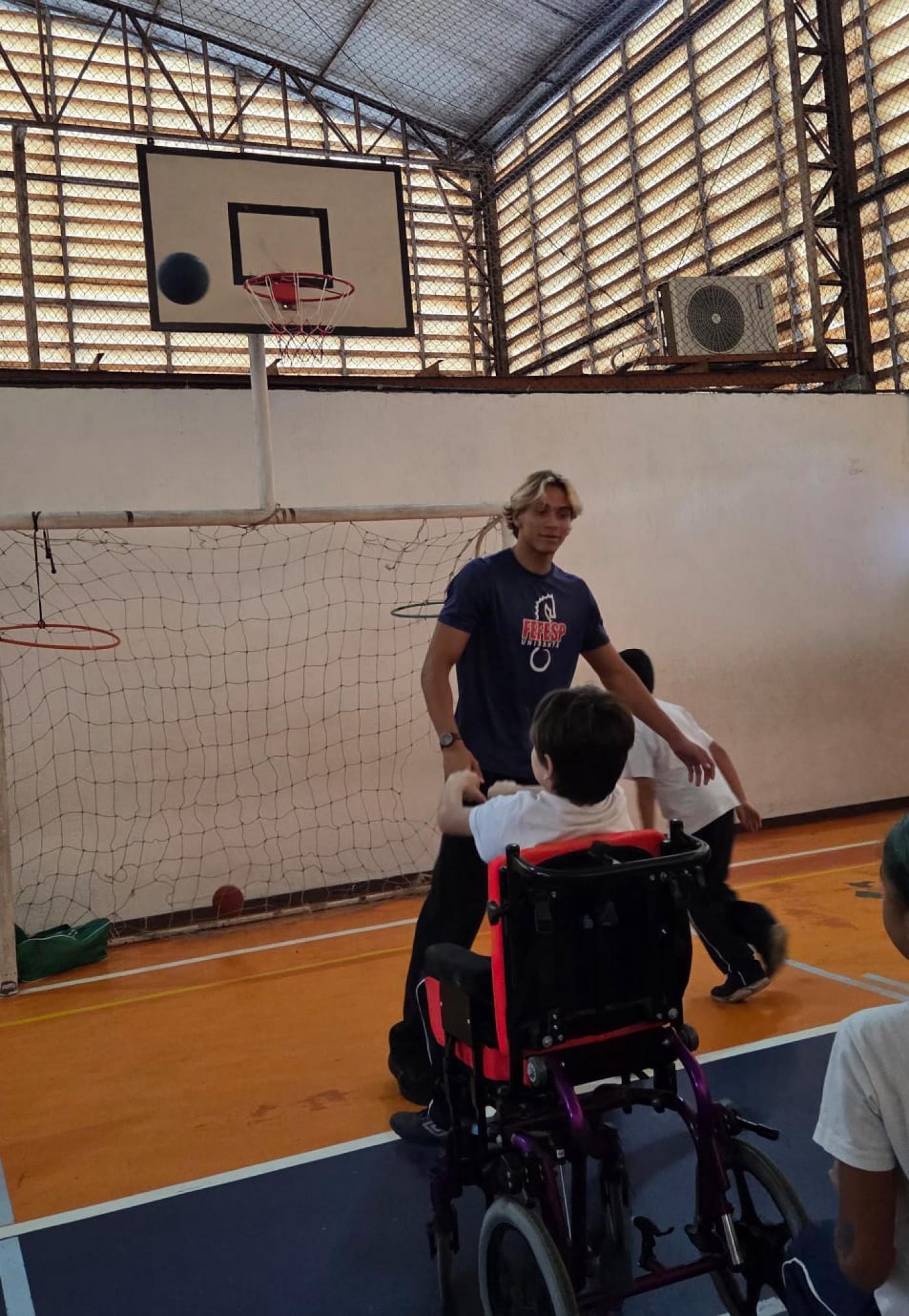 criança em cadeira de rodas brinca com instrutor. #paratodosverem