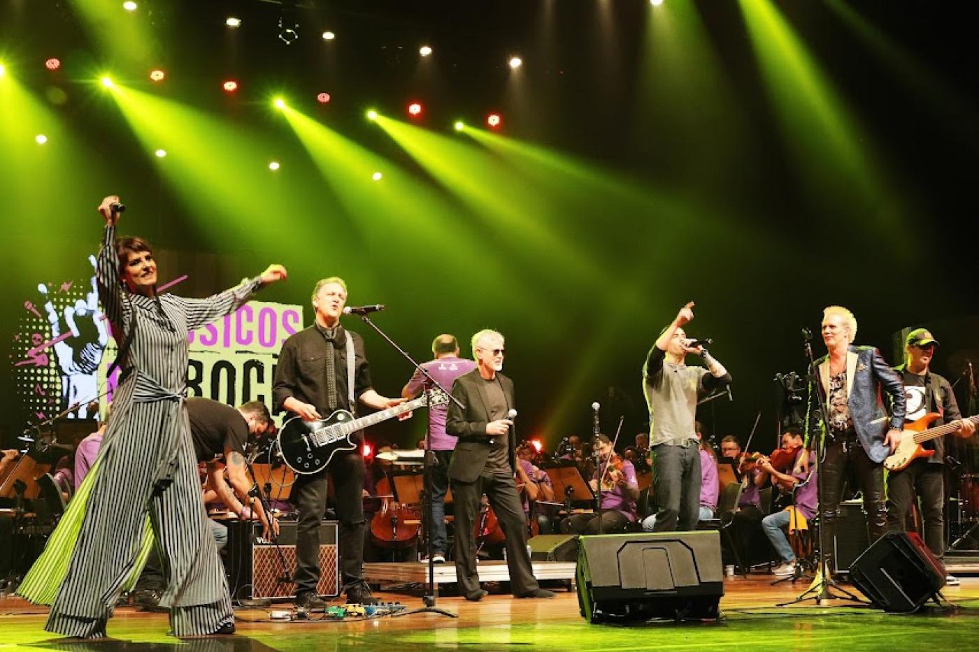 cantores estão no palco com orquestra sinfônica ao fundo. #paratodosverem