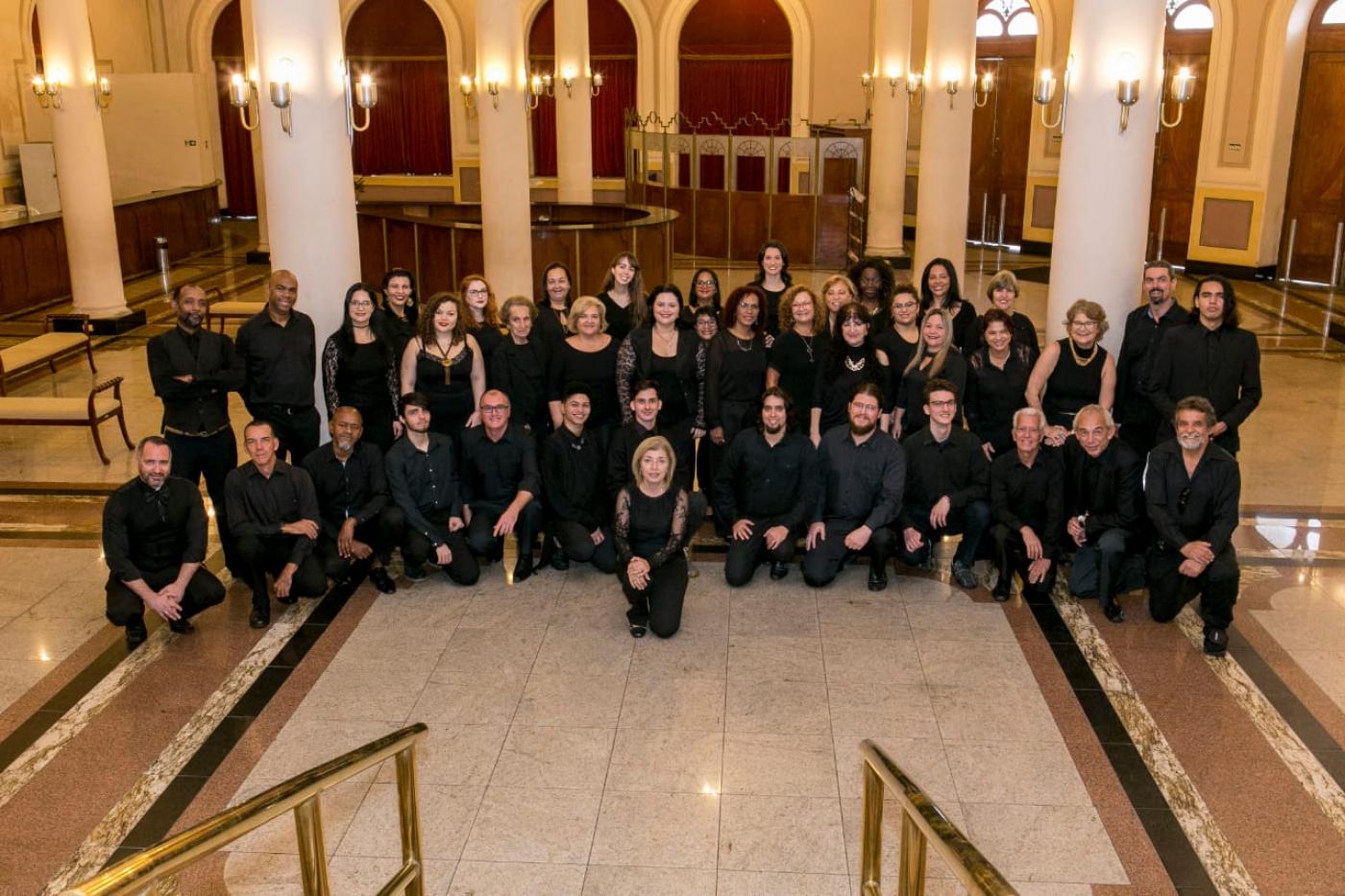 Com 40 integrantes entre homens e mulheres, coral posa para foto em entrada de teatro