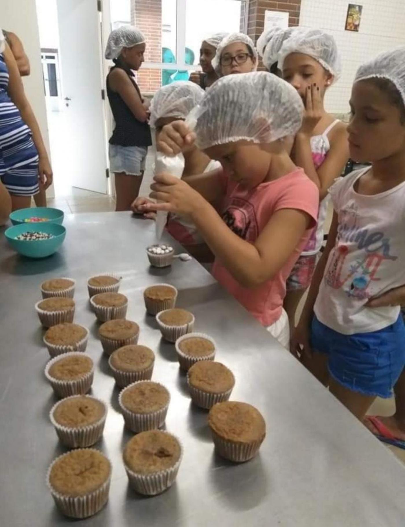 crianças estão decorando cupcakes. #paratodosverem 