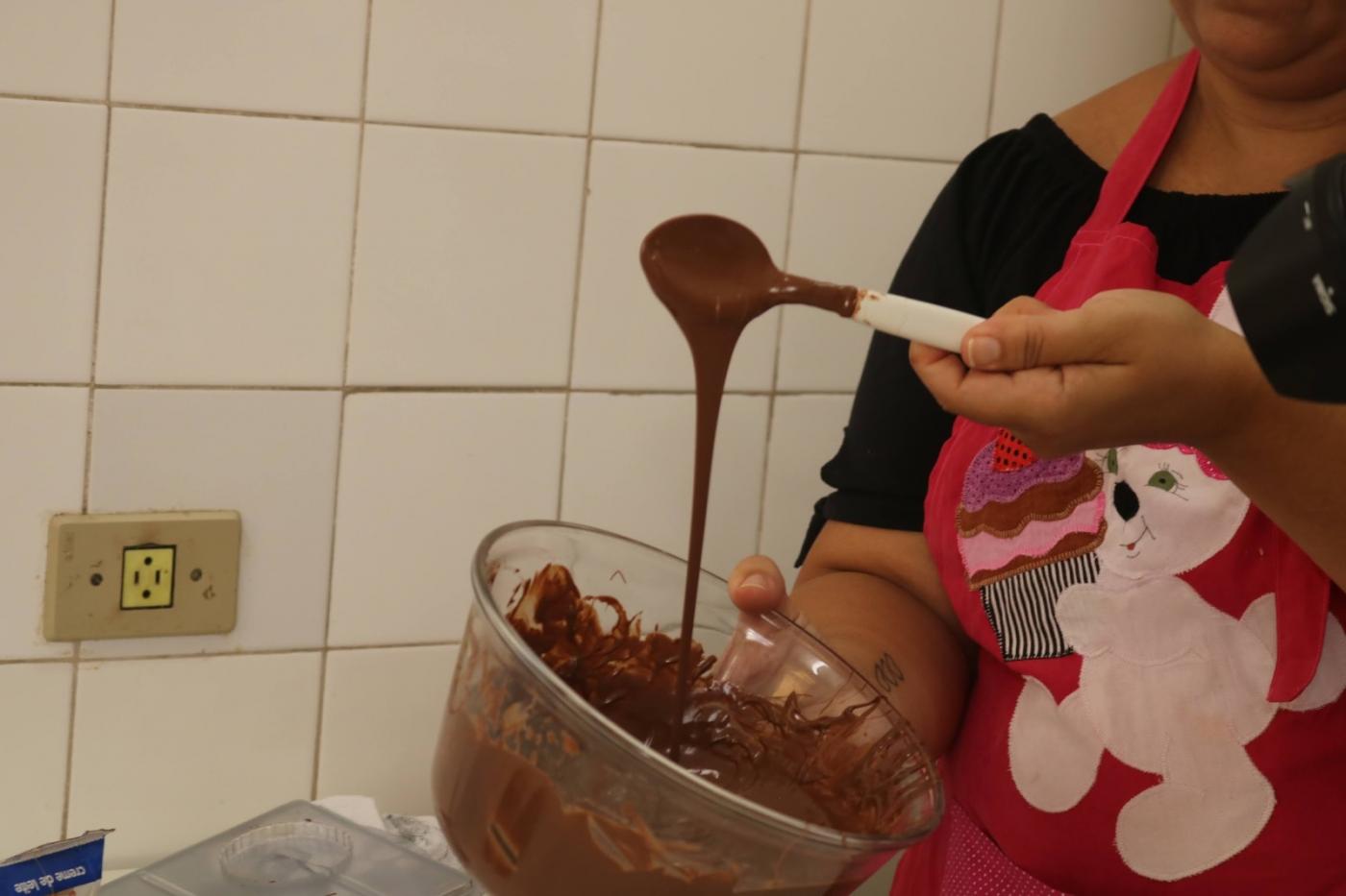 mão mexe em calda de chocolate dentro de vasilha. #paratodosverem