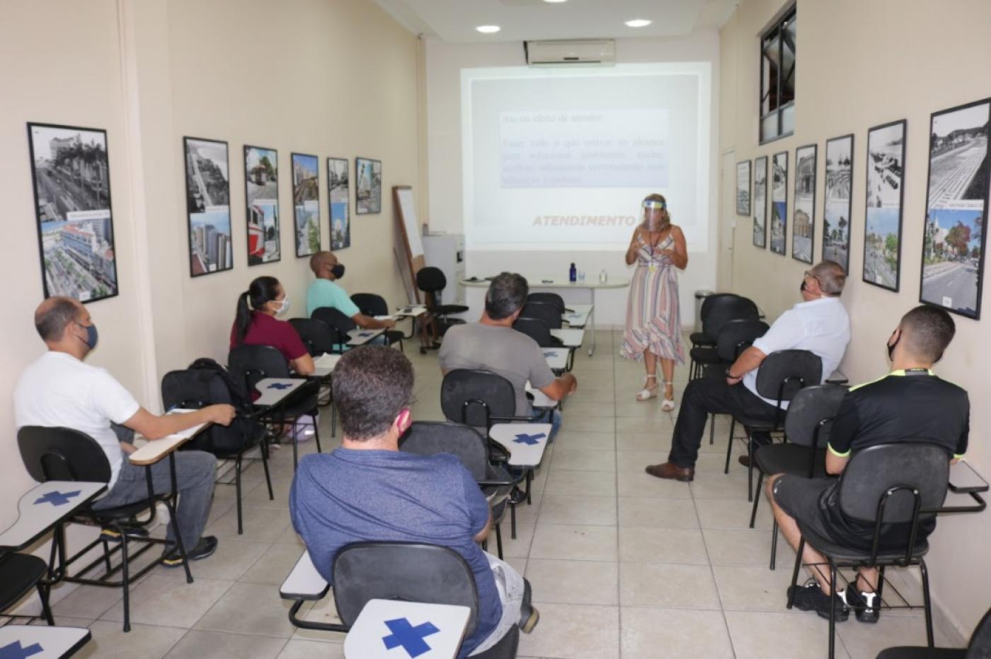 pessoas sentadas em sala observam explicações de palestrante #paratodosverem