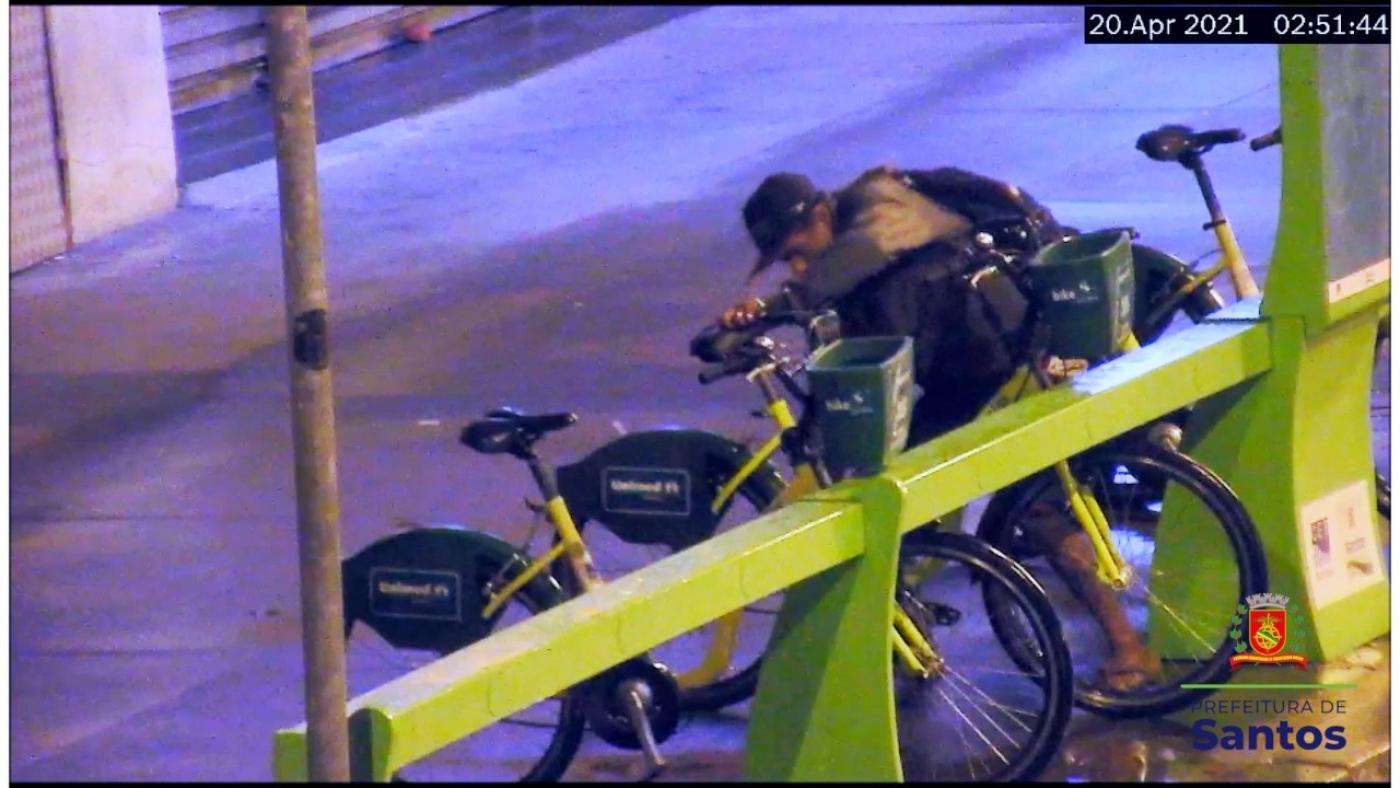 em imagem de câmera,rapaz mexe em estação do  bike santos #paratodosverem