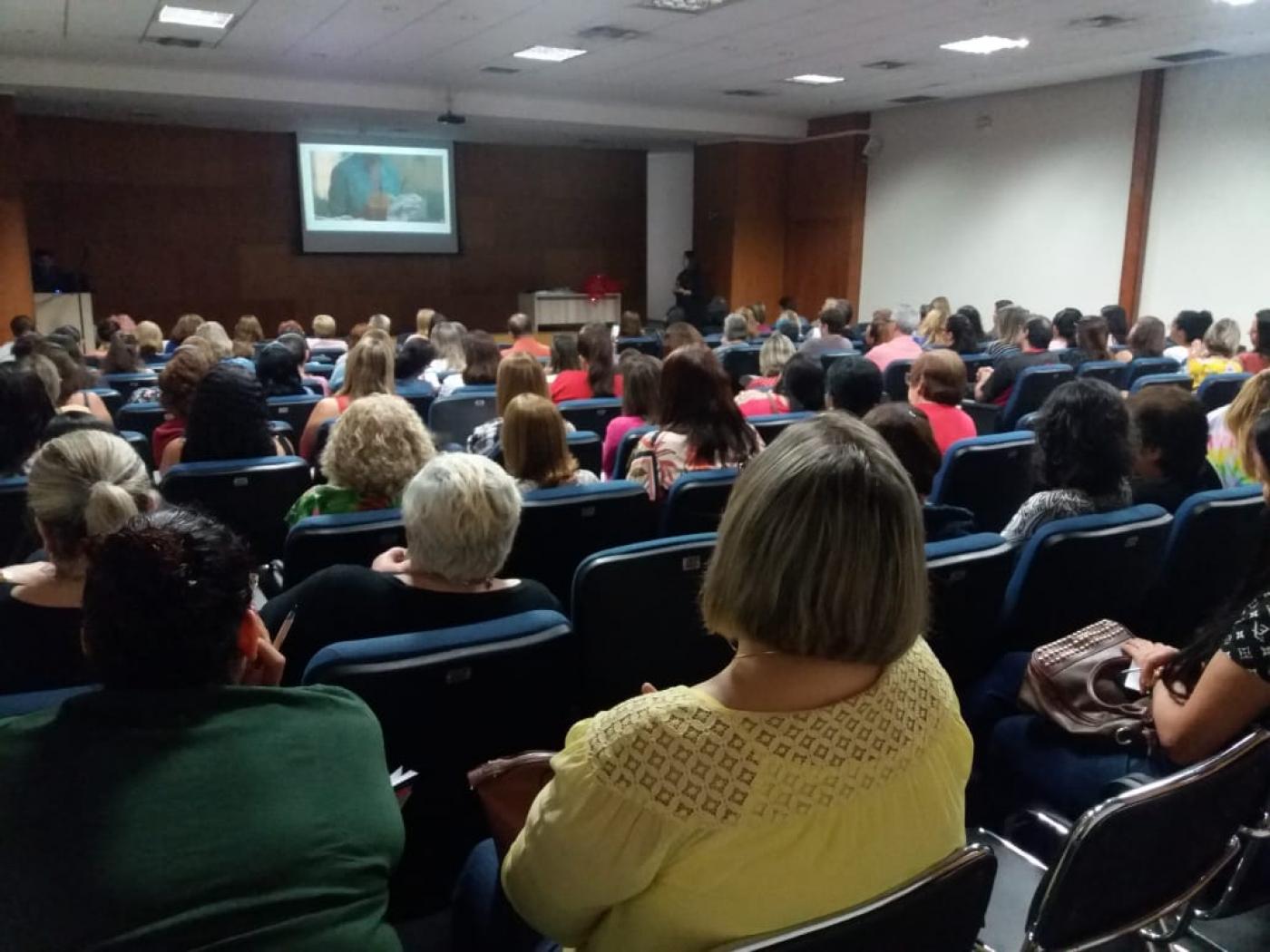 Auditório lotado de pessoas assistindo palestra. #pracegover