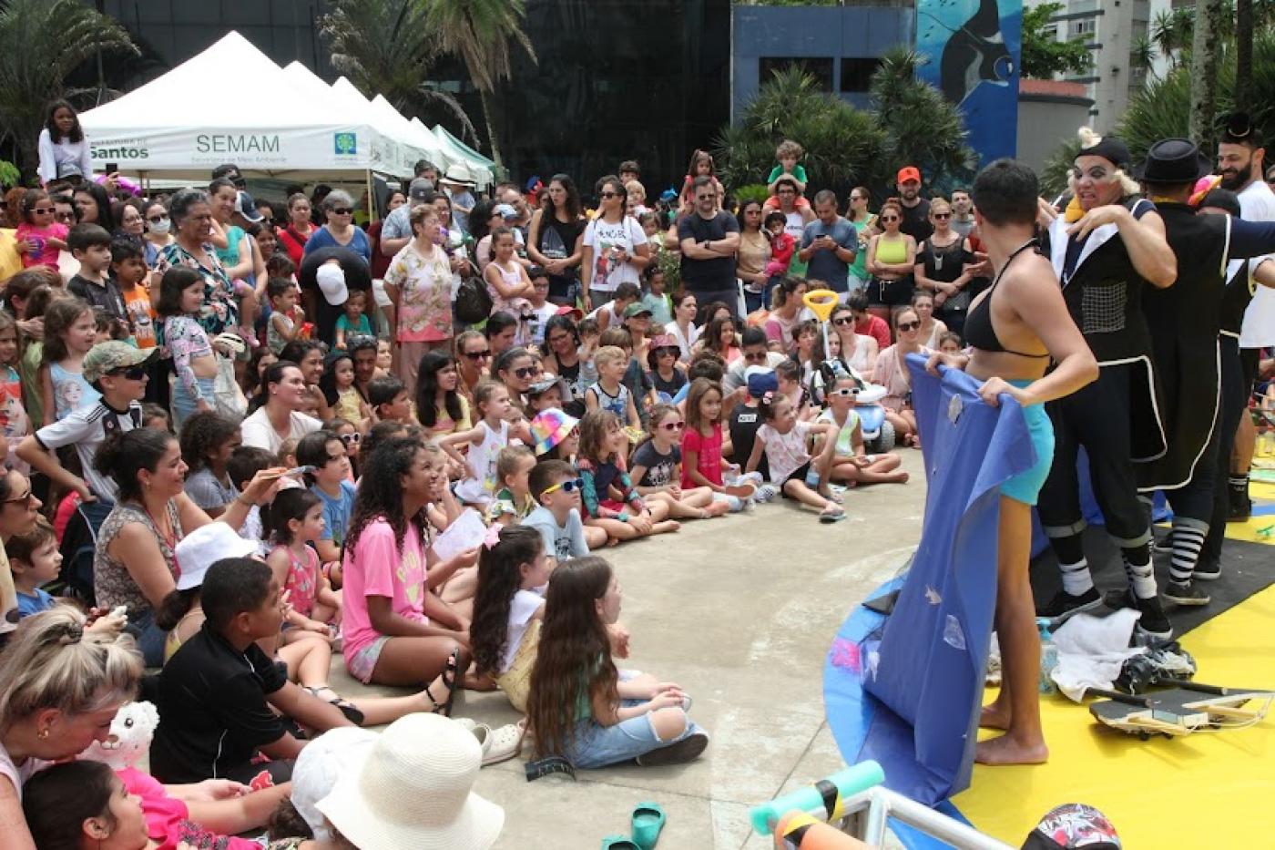 Crianças assistem apresentação em praça ao lado do Aquário. #paratodosverem