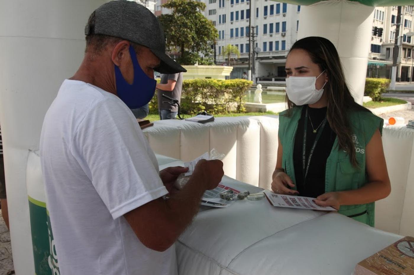 Munícipe recebe sachê de sal grosso e panfletos em tenda montada no Gonzaga. #pracegover