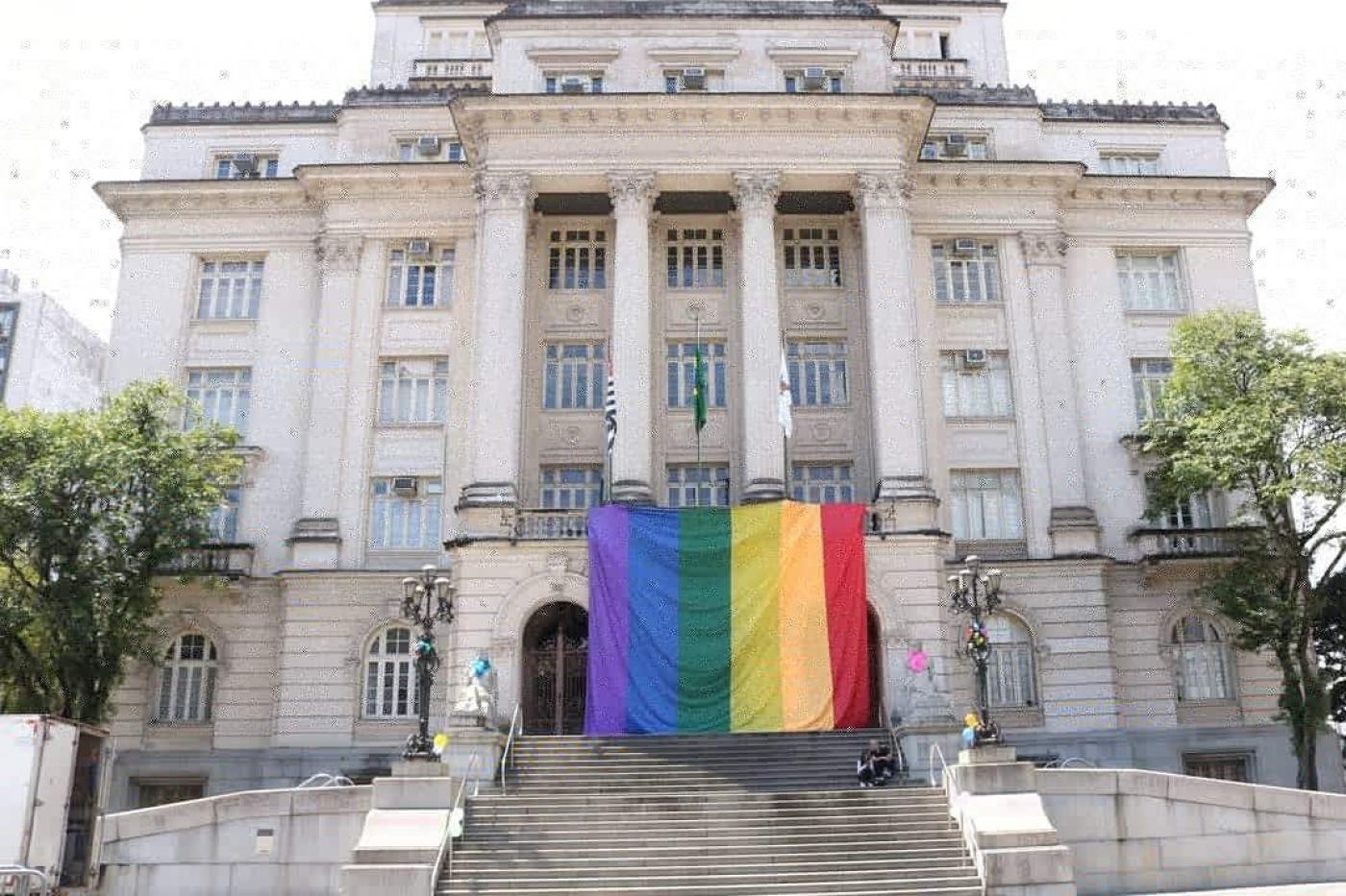 Fachada da Prefeitura com grande bandeira do Orgulho LGBTQIA+ #Paratodosverem