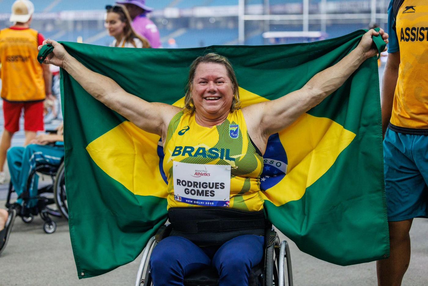 a atleta de braços aberto segurando a Bandeira do Brasil. #paratodosverem