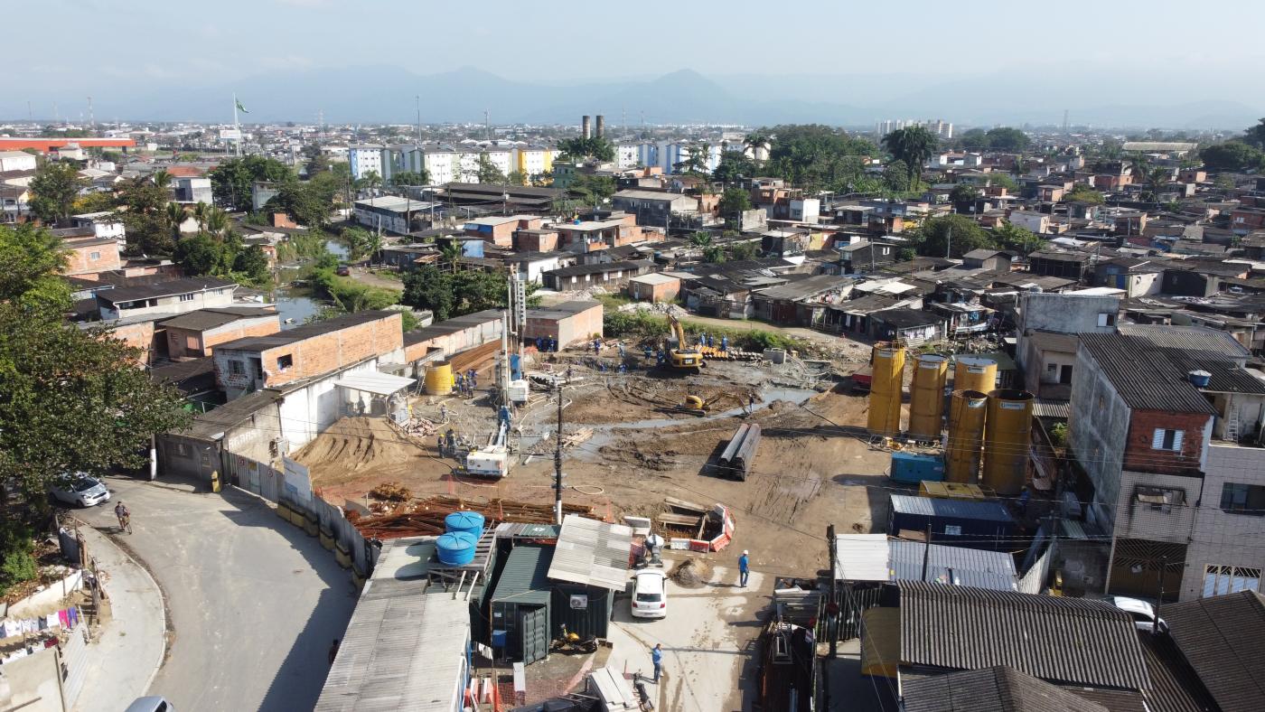 imagem aérea da obra com maquinário dentro e ao fundo casas #paratodosverem