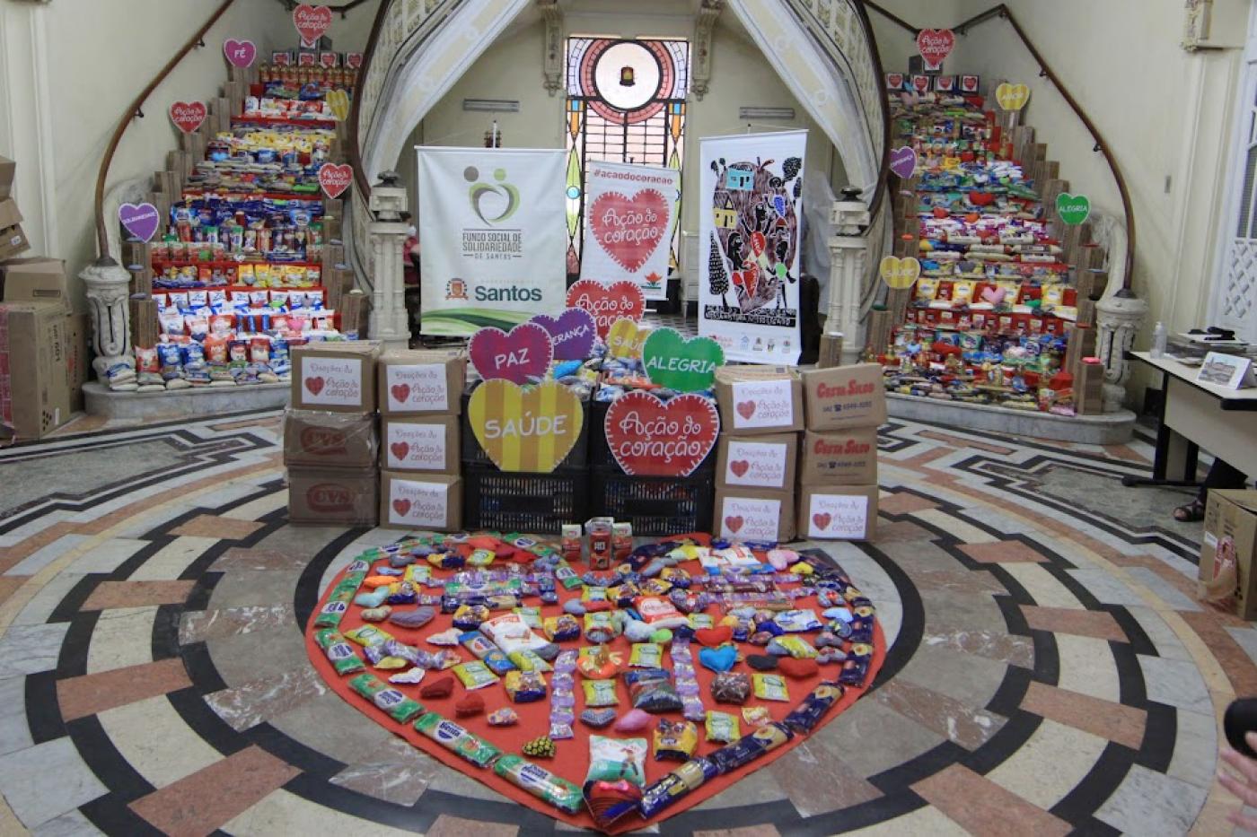 pacotes de alimentos enchem degraus de escadas e parte de um saguão. #paratodosverem