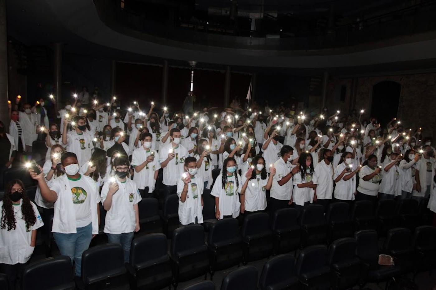Estudantes com jaleco branco erguem vela #paratodosverem