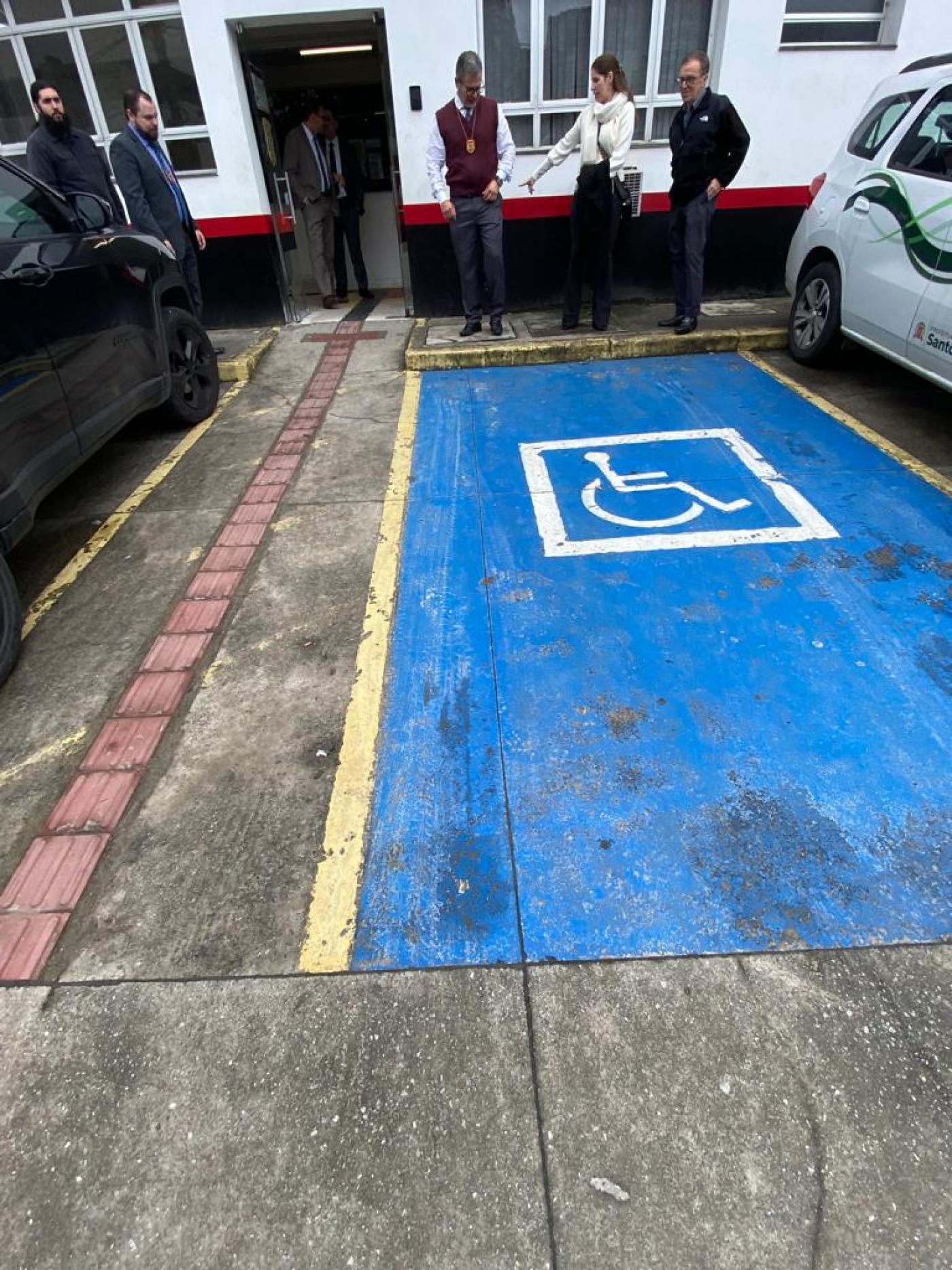 Vaga para estacionamento de veículos de pessoas com deficiências e pessoas ao fundo. #paratodosverem