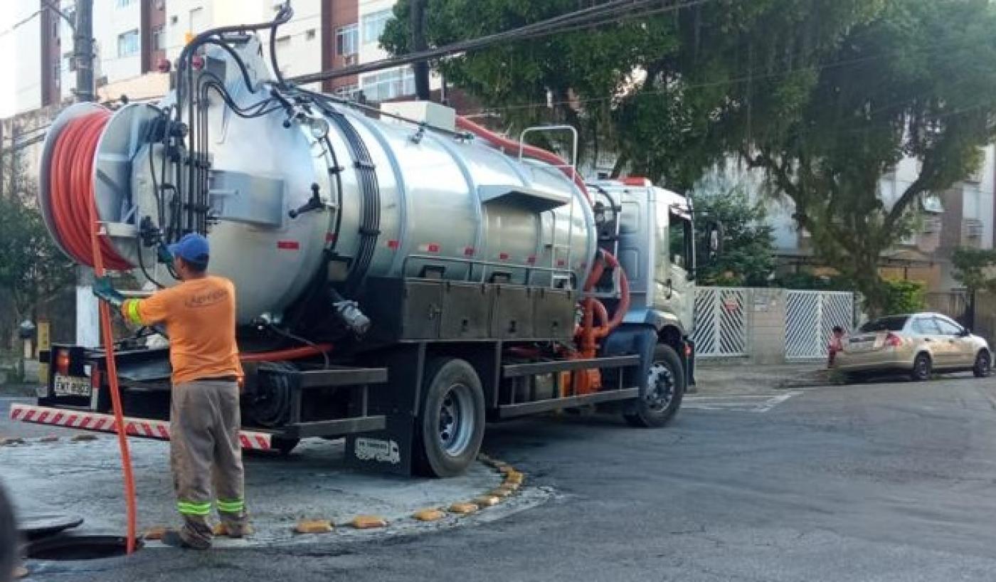 caminhão hidrojato está parado enquanto homem está limpando bueiro. #paratodosverem
