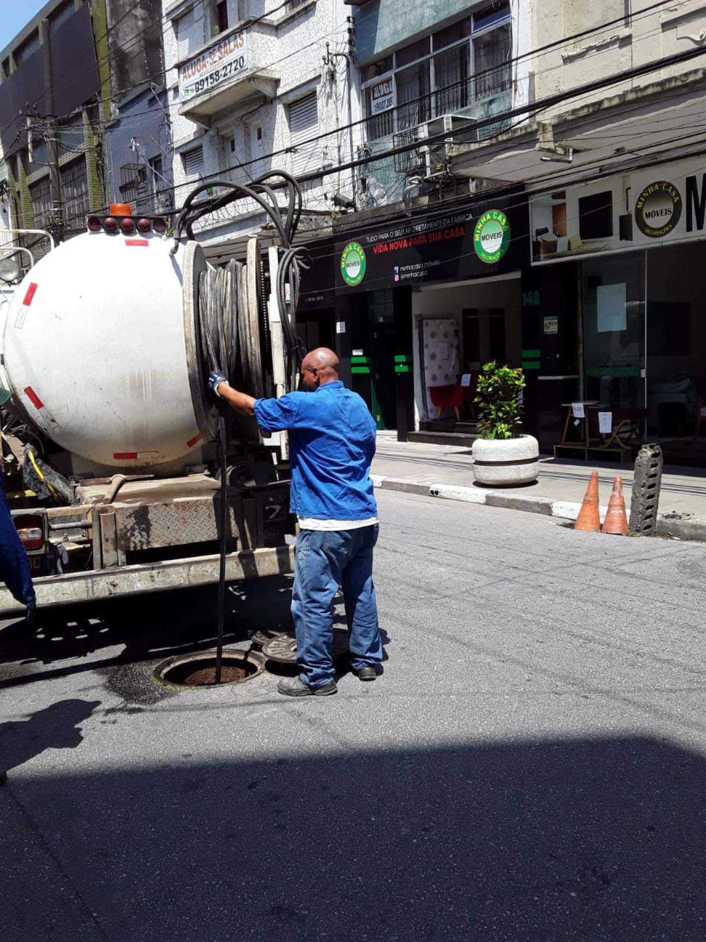 Homem opera equipamento de hidrojateamento de caminhão em galeria na rua. #pratodosverem