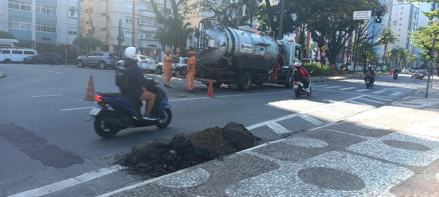 caminhão para serviços de drenagem está na avenida. junto à guia há um monte de areia. #paratodosverem