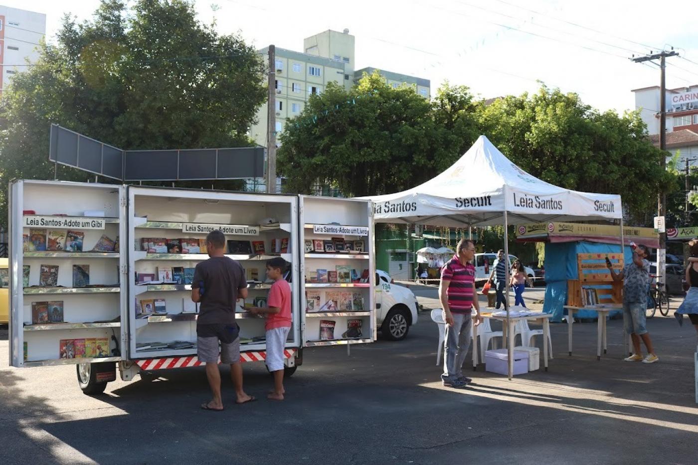 biblioteca móvel parada em praça com pessoas escolhendo livros - foto: arquivo/PMS