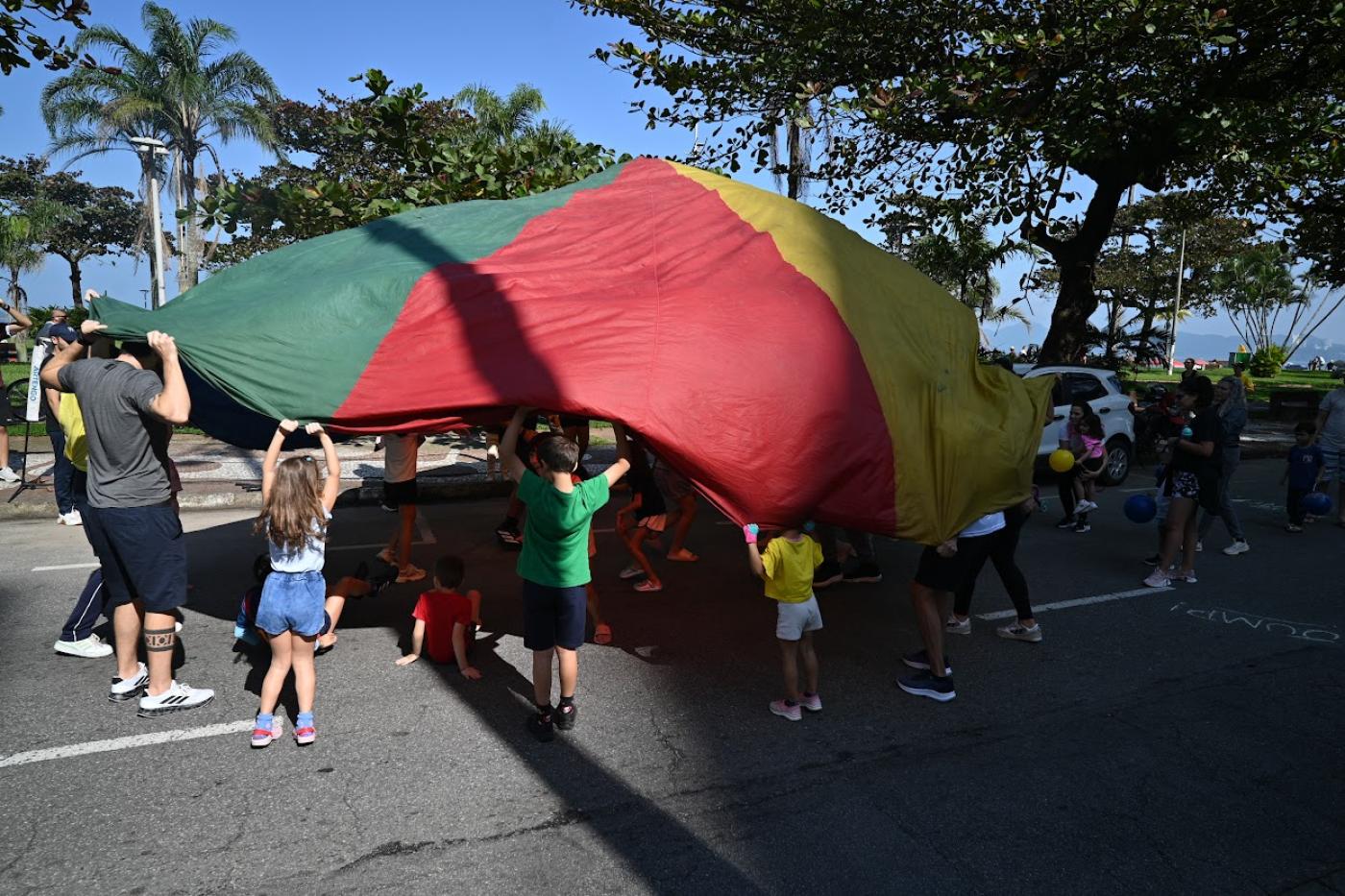 crianças brincando com lona colorida #paratodosverem