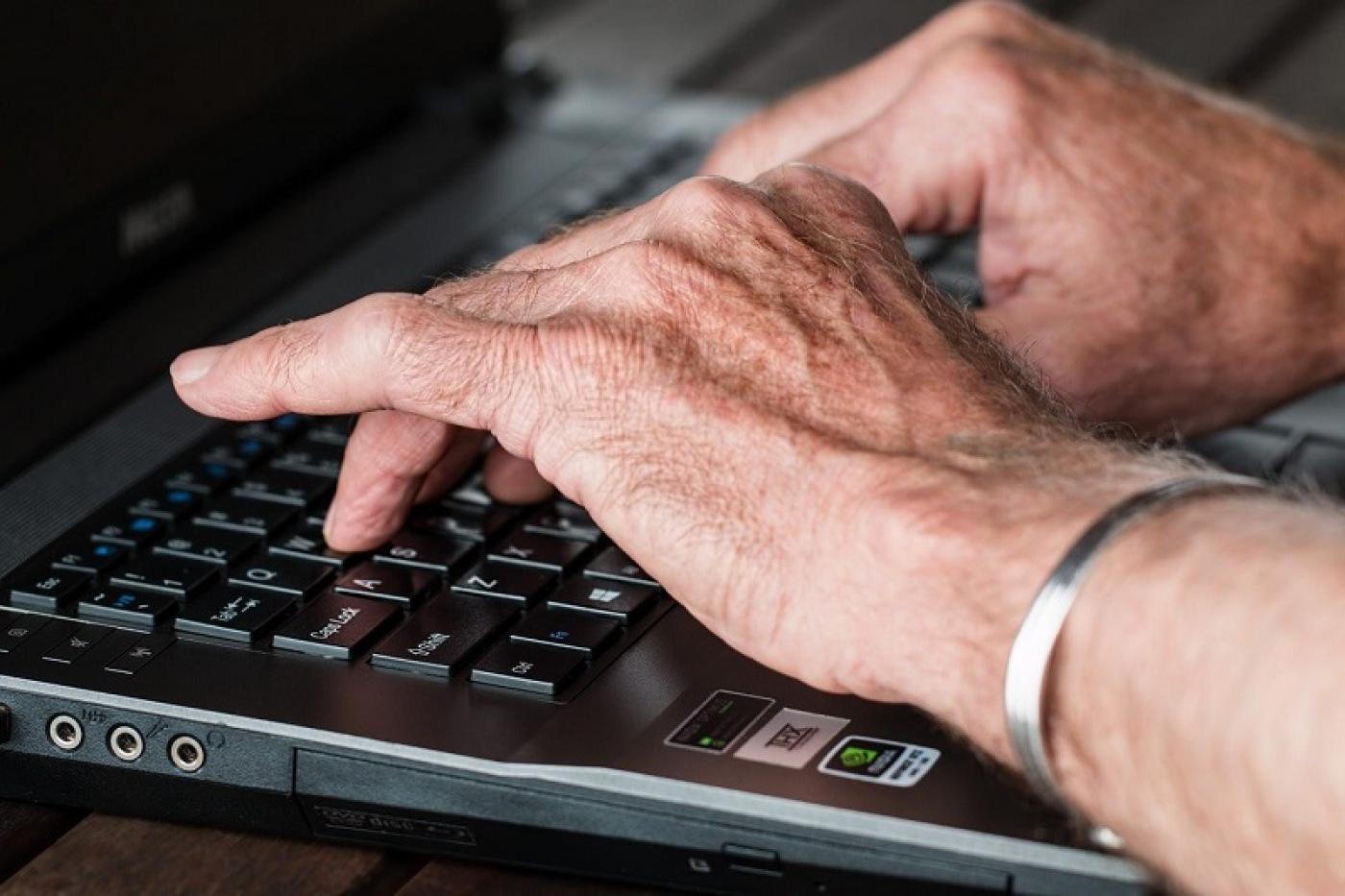 mãos de pessoa idosa digitando em computador. #paratodosverem 