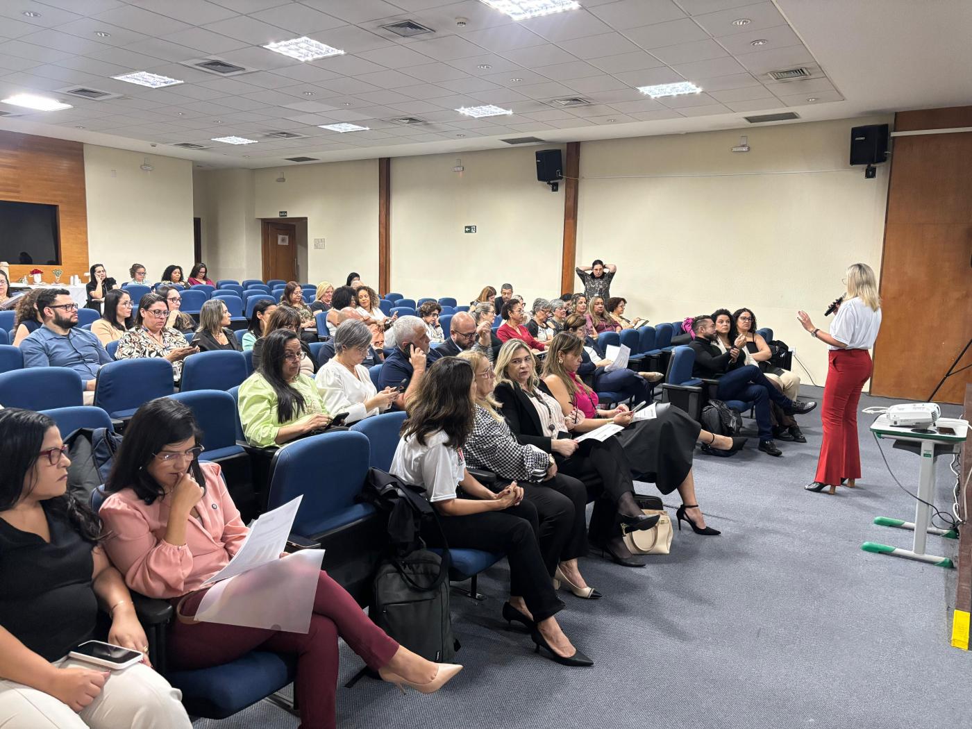 uma pessoa em pé falando e outras sentadas #paratodosverem
