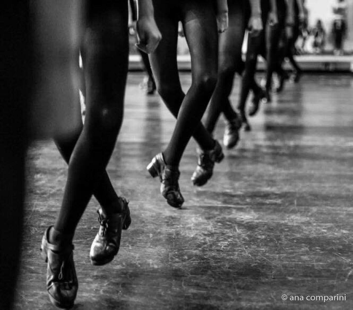 Close em pés de bailarinas de sapateado. Todos estão cruzados e no ar. #Pracegover