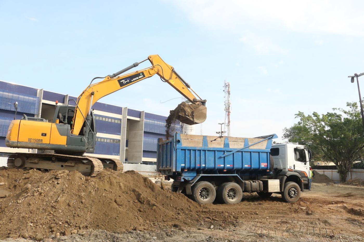 máquina coloca areia em caminhão #paratodosverem