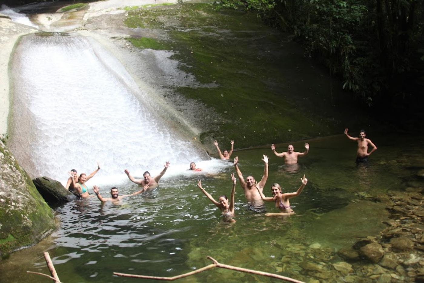 turistas estão na água, logo abaixo de tobogã todos estão com as mãos para cima se divertindo. #paratodosverem