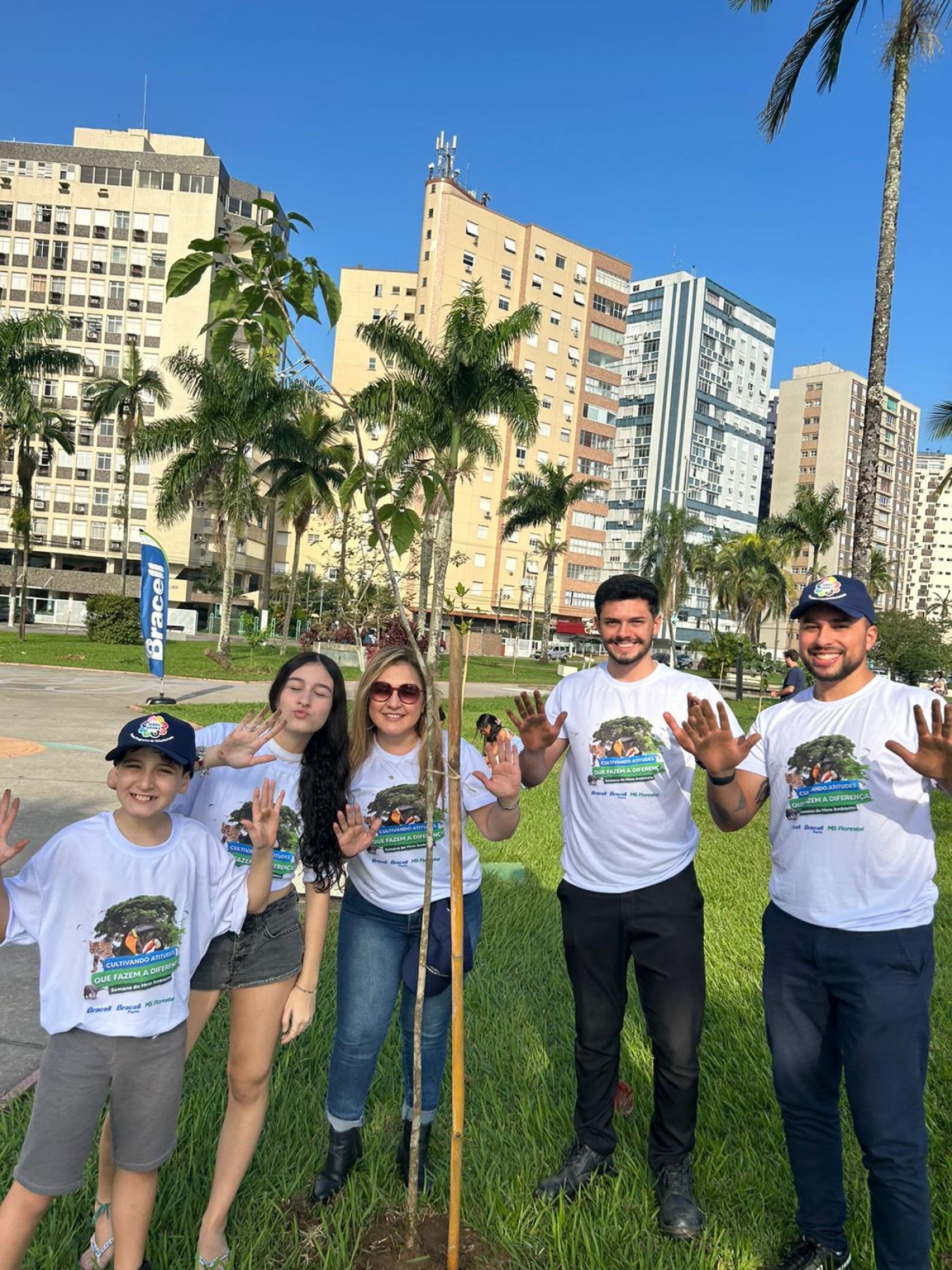 voluntários posam ao lado de árvore #paratodosverem