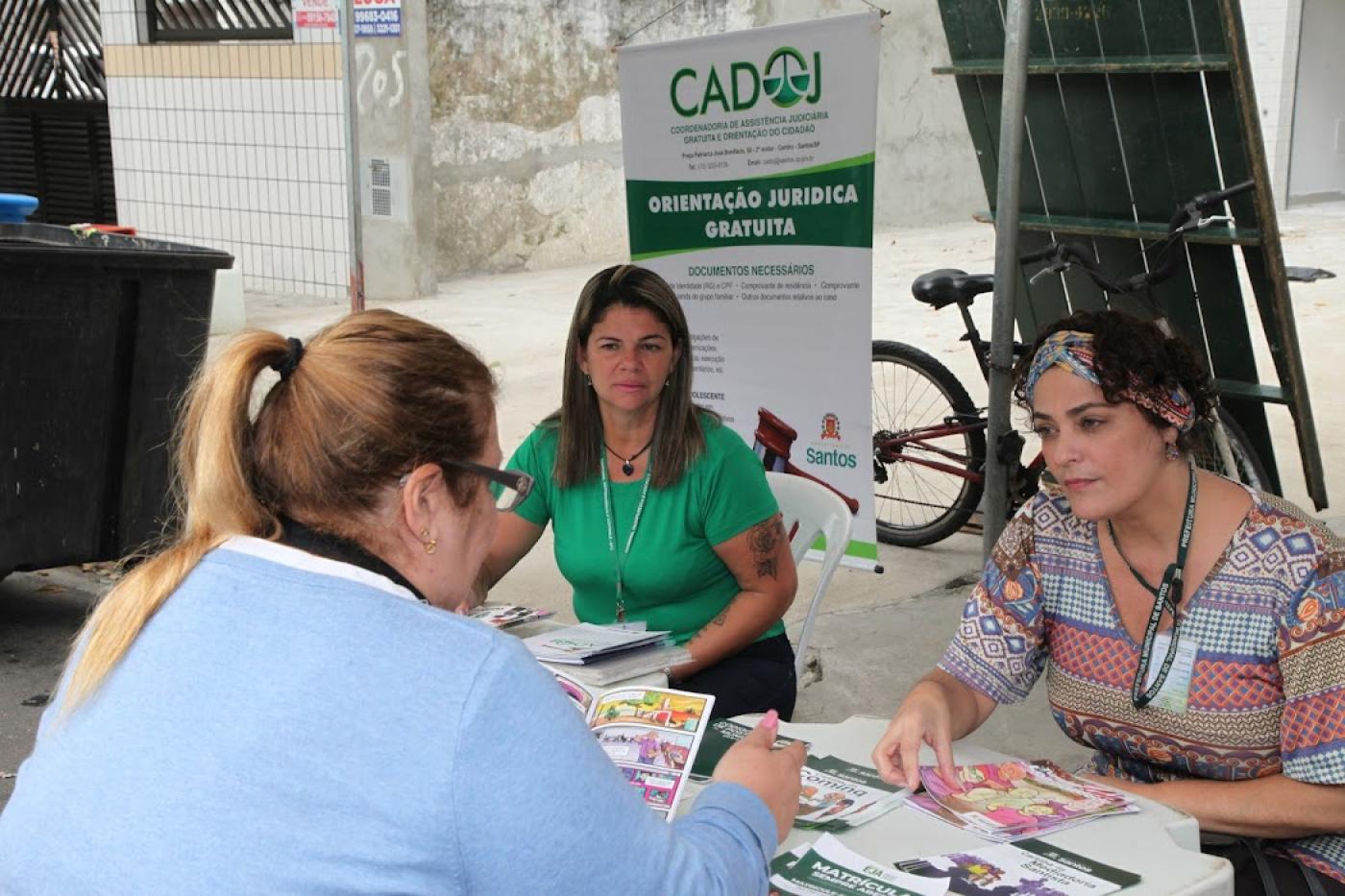 Feirante é orientada em tenda e olha material informativo. #pratodosverem