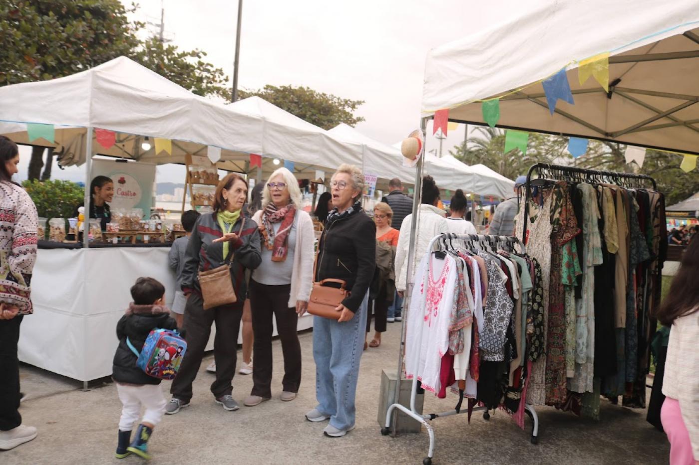 pessoas andando em meio a barracas #paratodosverem