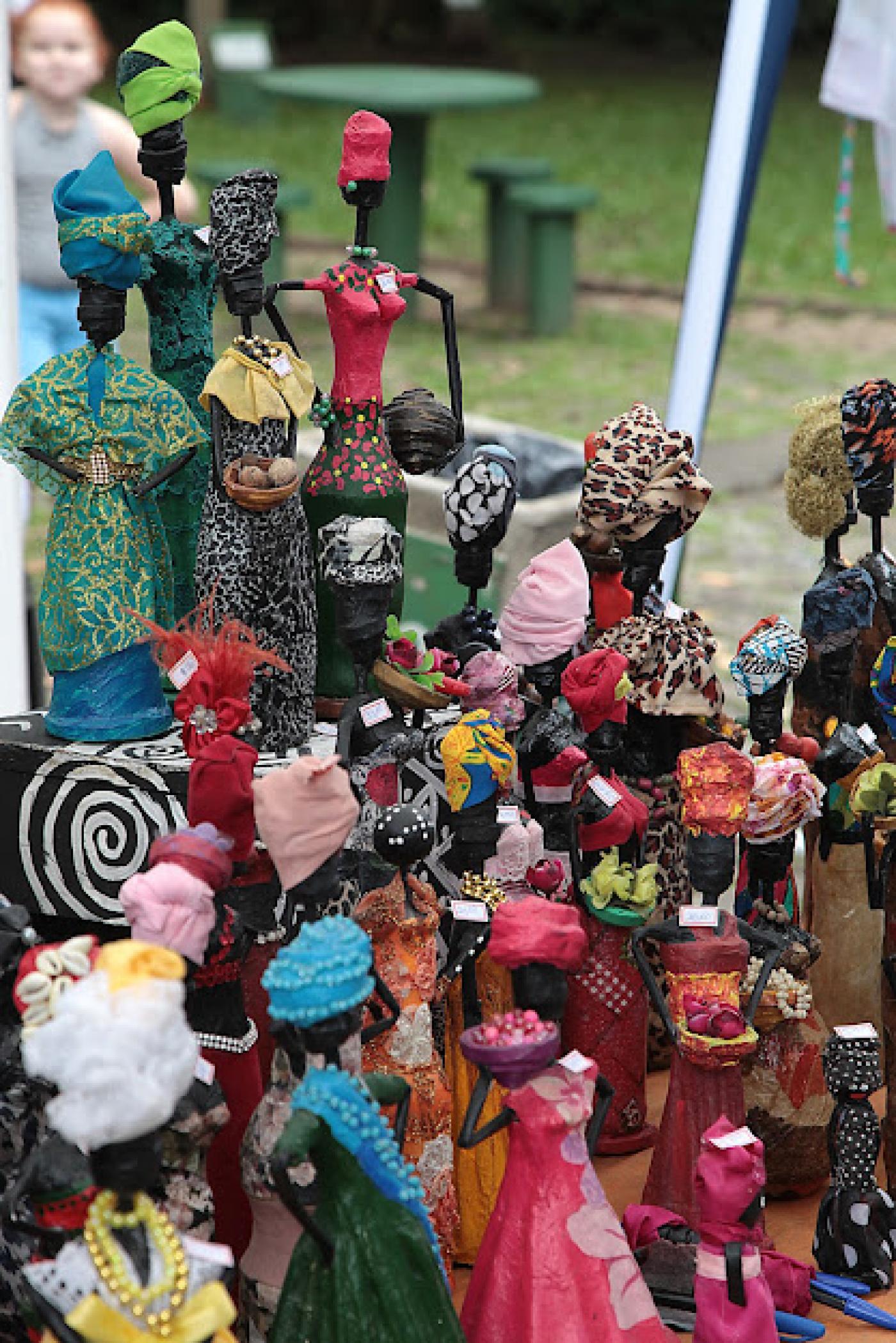 Bonecas negras com roupas afros coloridas em estande da feira. #pratodosverem