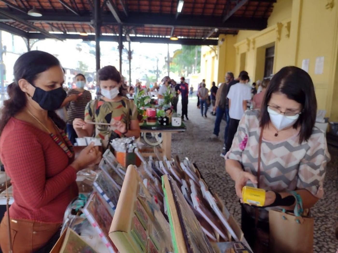 Mulher compra produto em feira #paratodosverem