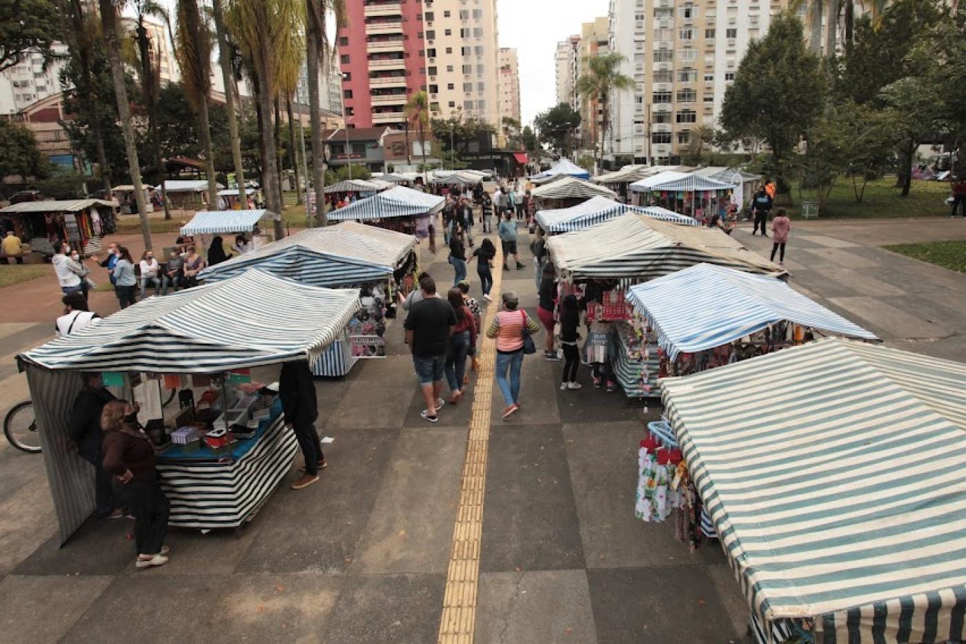 barracas da feirart em praça com movimentação de pessoas. #paratodosverem