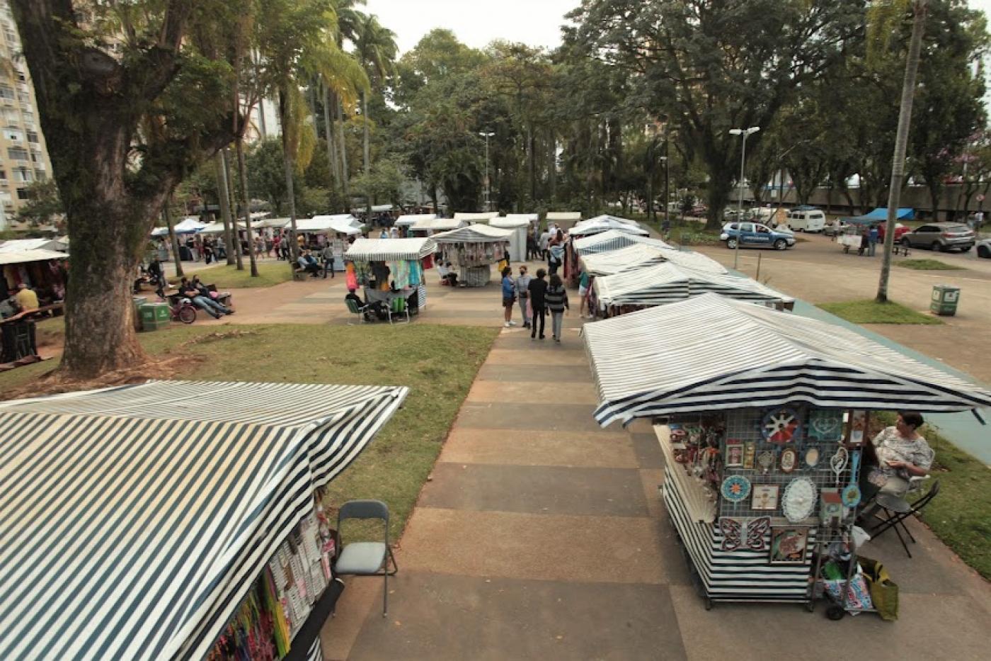 barracas da feirart montadas em praça. Foto pelo alto mostra cobertura idêntica de lona das barracas. #paratodosverem