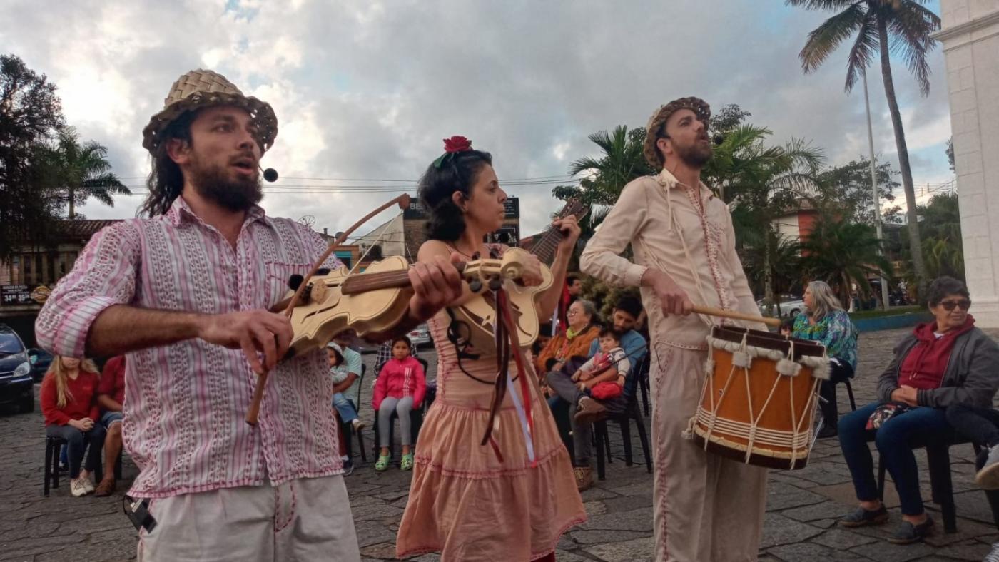 três integrantes de banda tocando numa rua. #paratodosverem