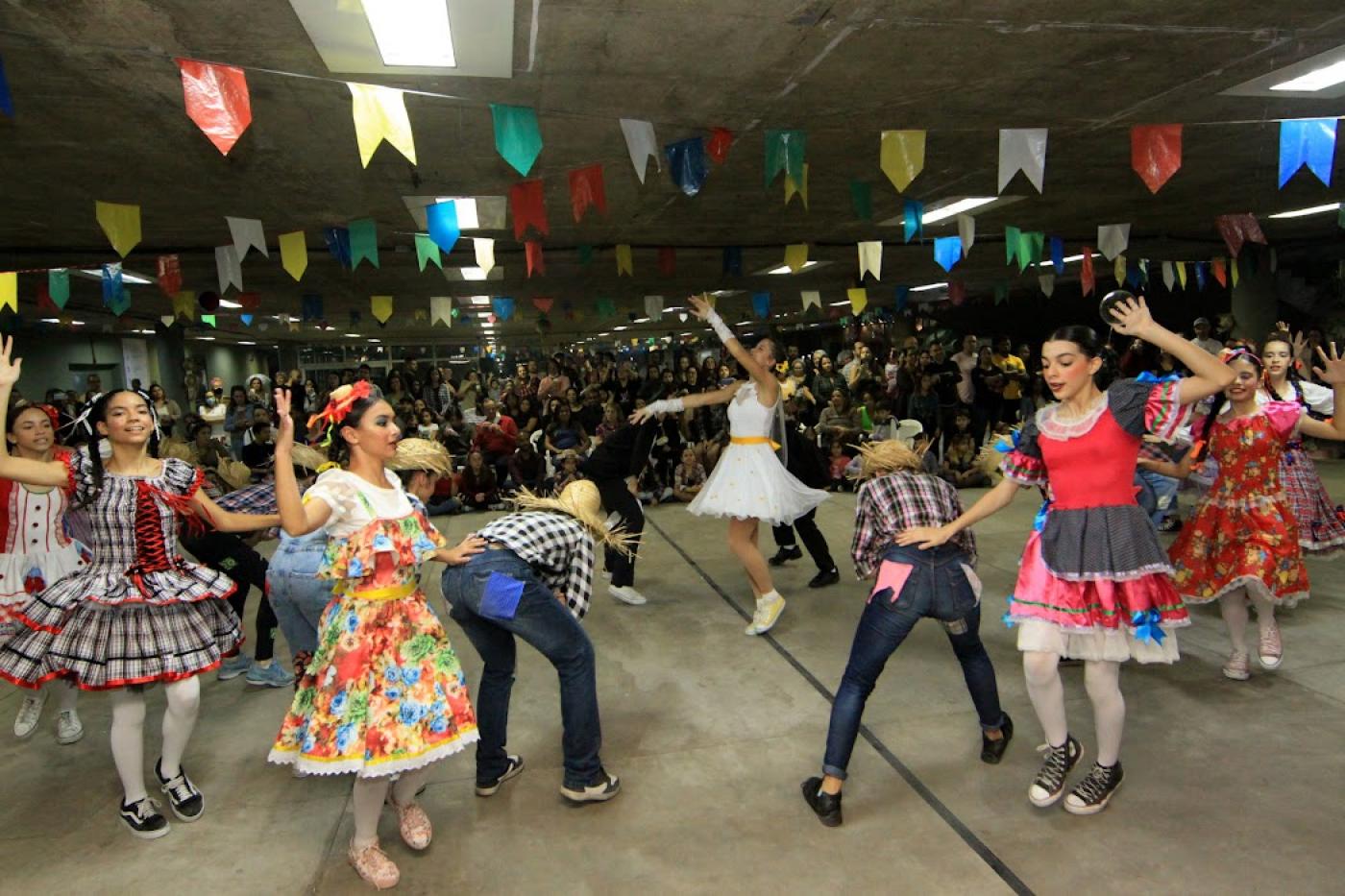bailarinos dançam quadrilha junina com pessoas assistindo ao fundo #paratodosverem