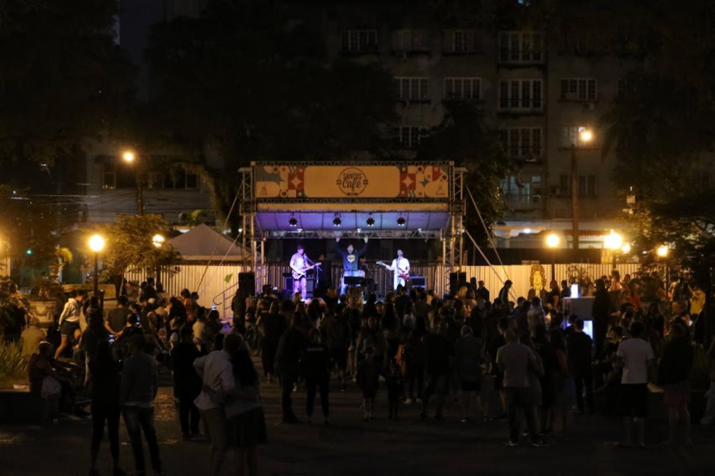 Público confere apresentação de banda, à noite, em palco montado na Praça Mauá. #pratodosverem