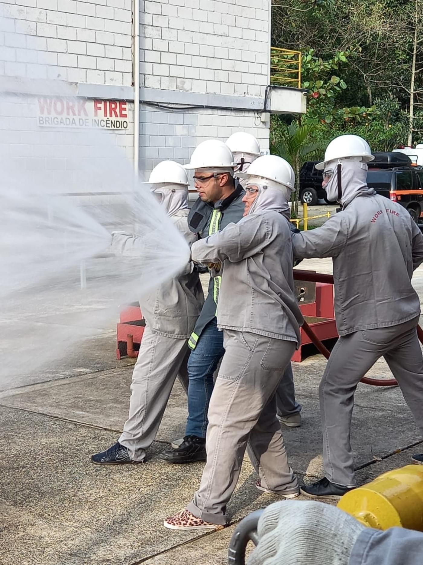 funcionários operam mangueira soltando água #paratodosverem 
