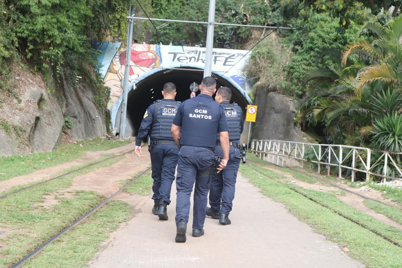 homens de costa andando em direção a túnel #paratodosverem