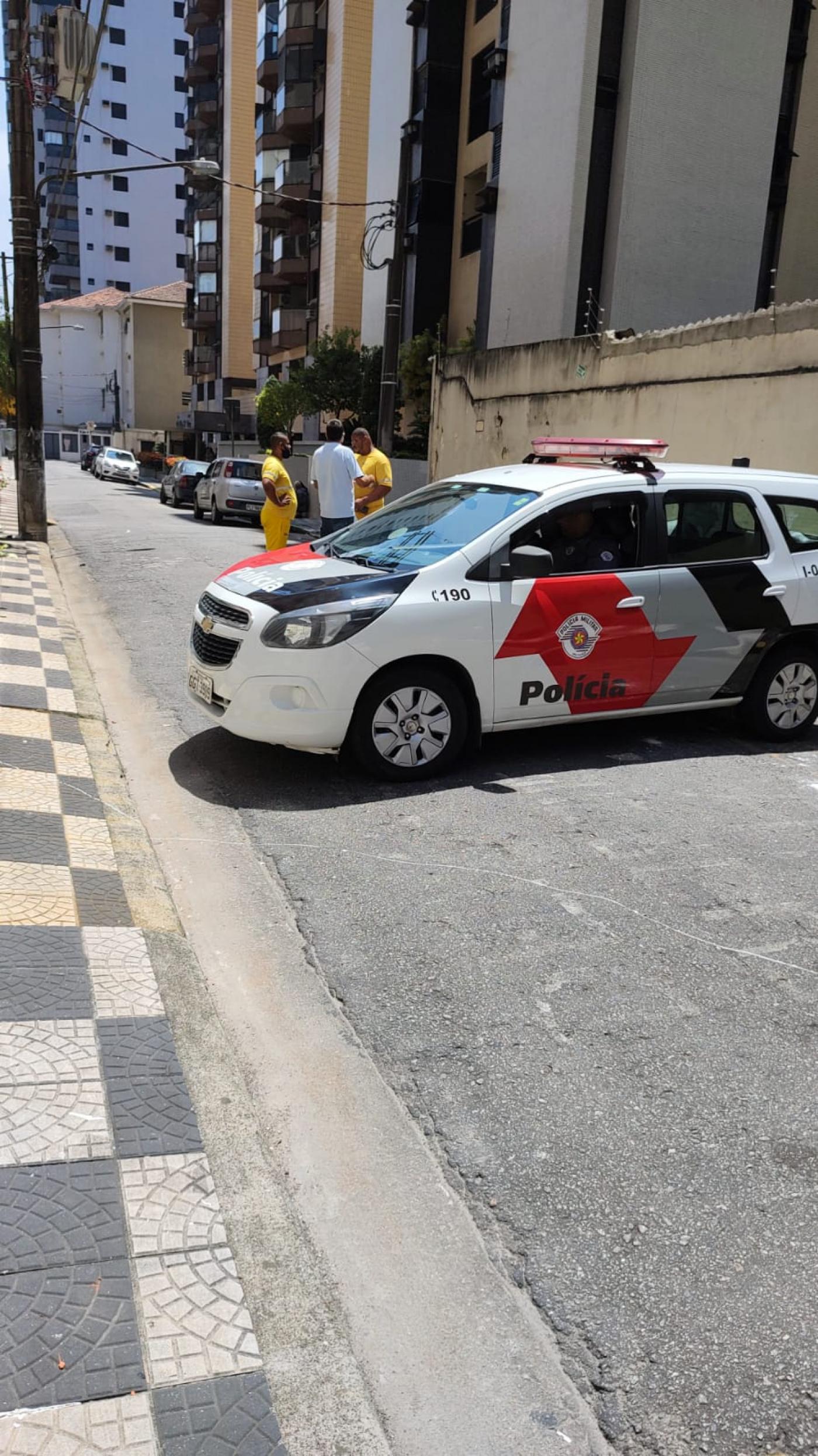 viatura da polícia em rua. Homens estão em pé atrás. #paratodosverem