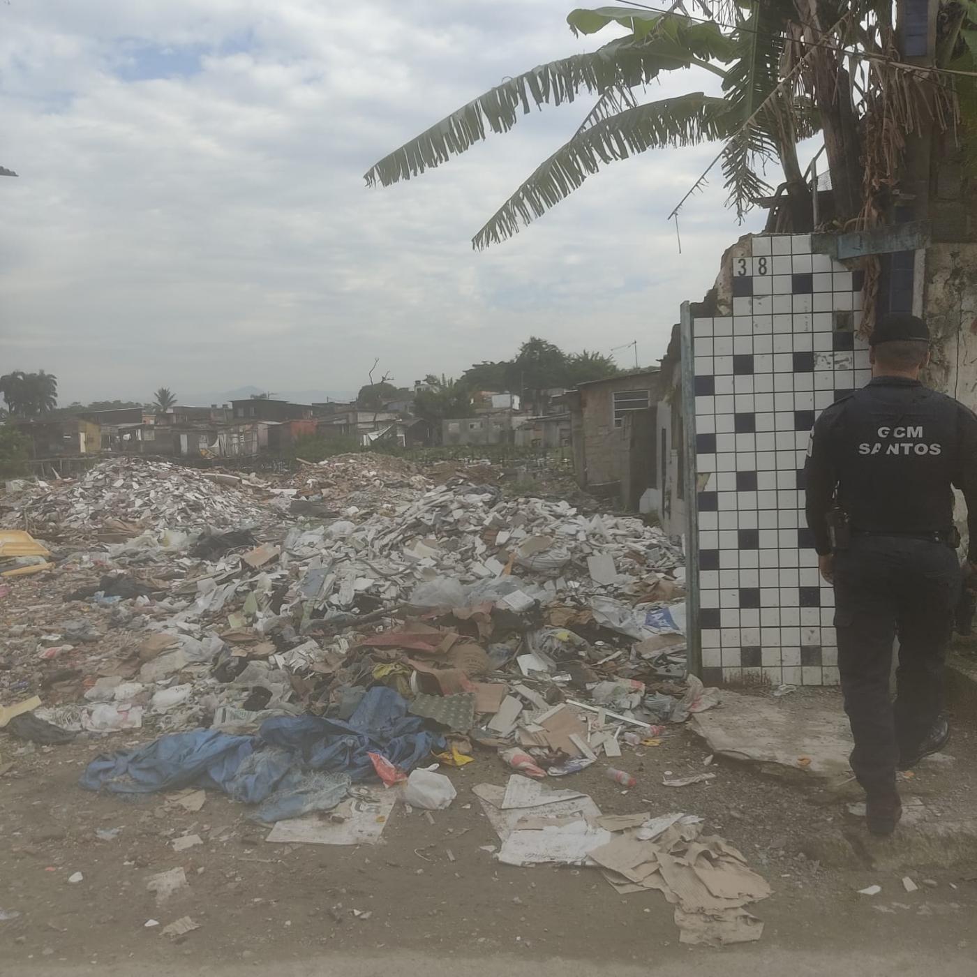 agente da guarda municipal está em pé próximo a um muro. à frente, restos de materiais de construção. #paratodosverem