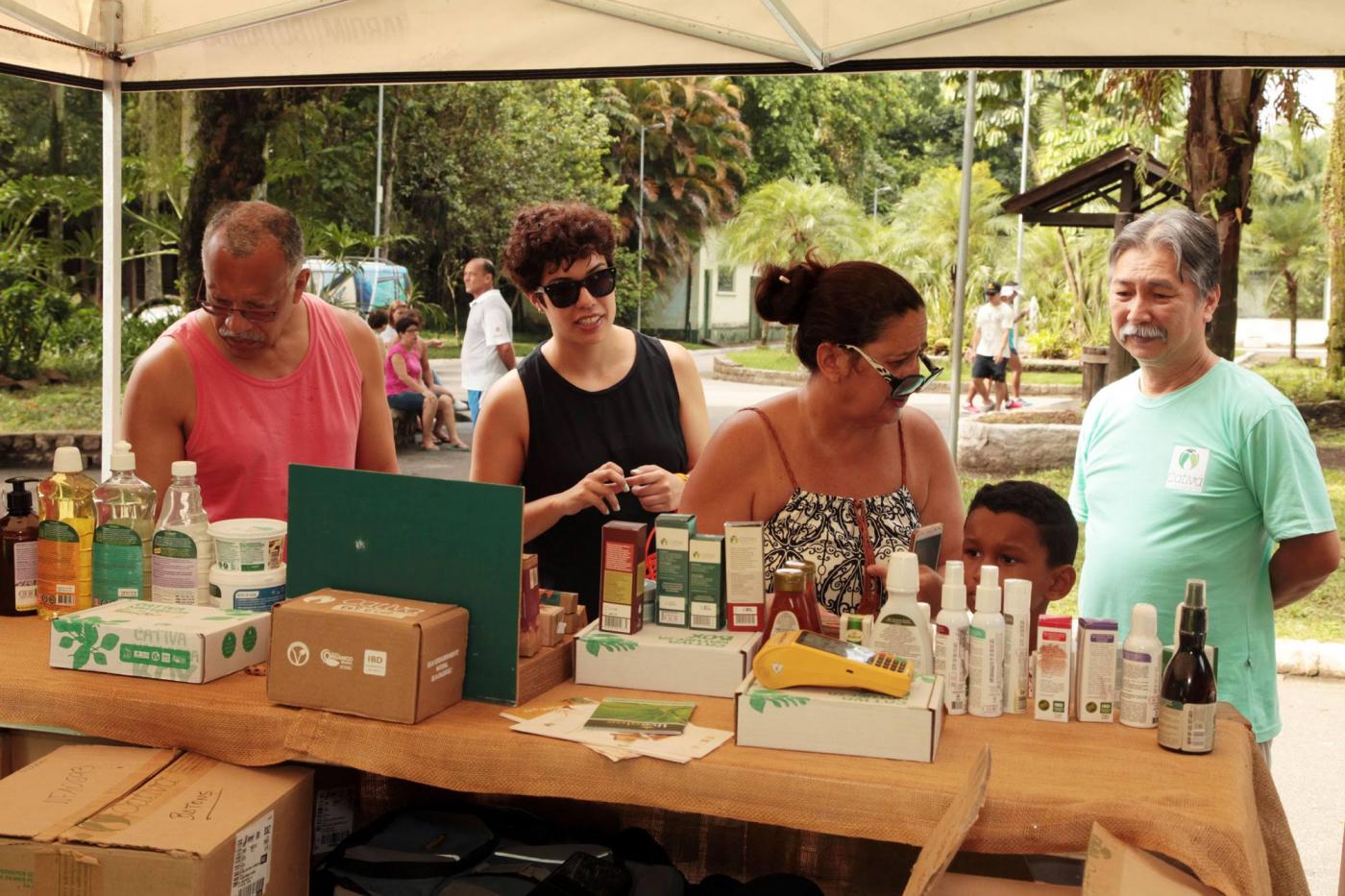 pessoas estão escolhendo produtos em barraca #pracegover 