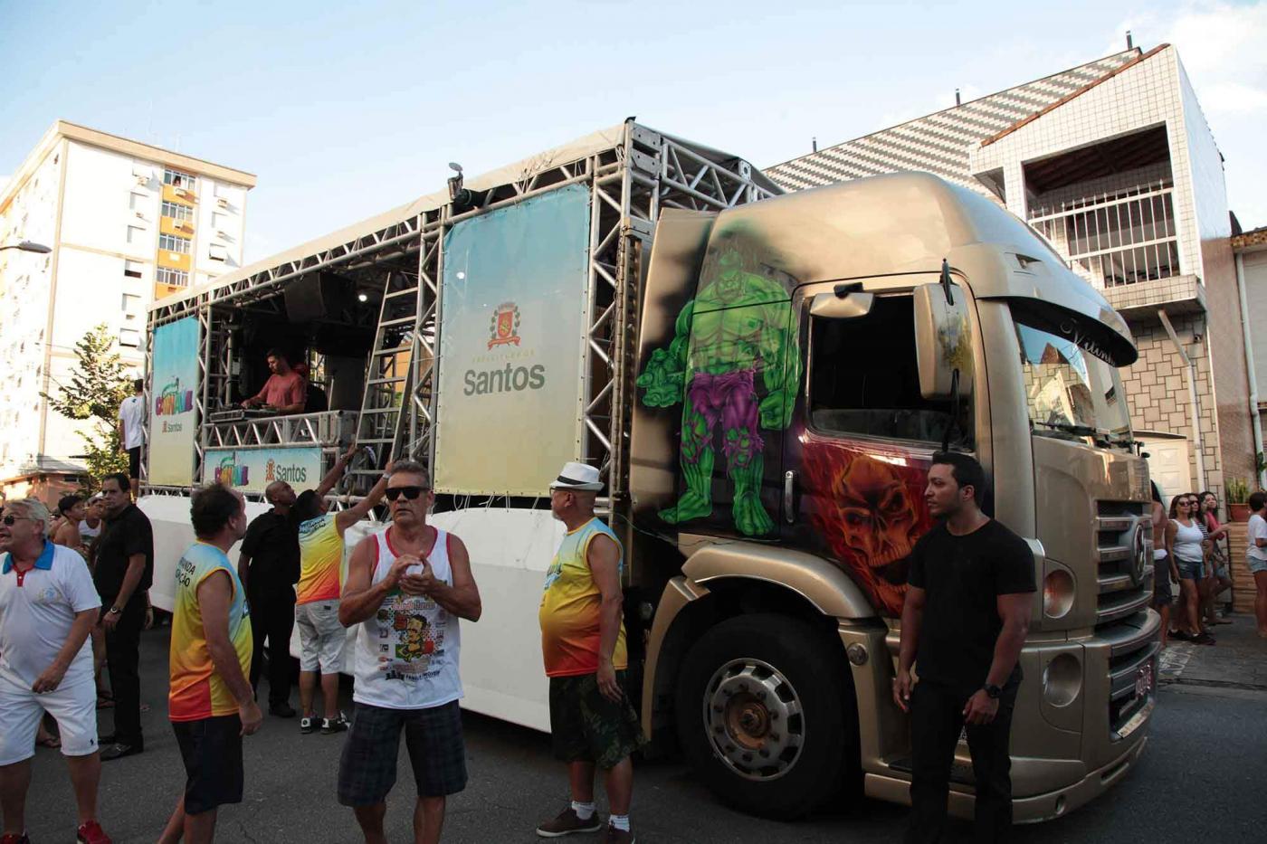 Carro de som na rua com alguns foliões ao lado. #Paratodosverem