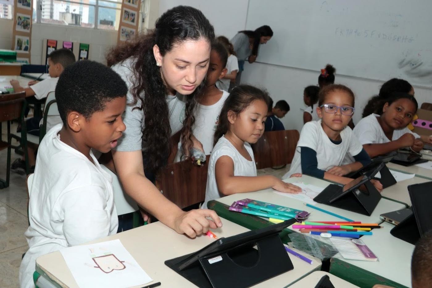 professora mostra tabtlet para aluno #paratodosverem 